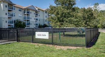 A black fence with a sign that says Bark Park.